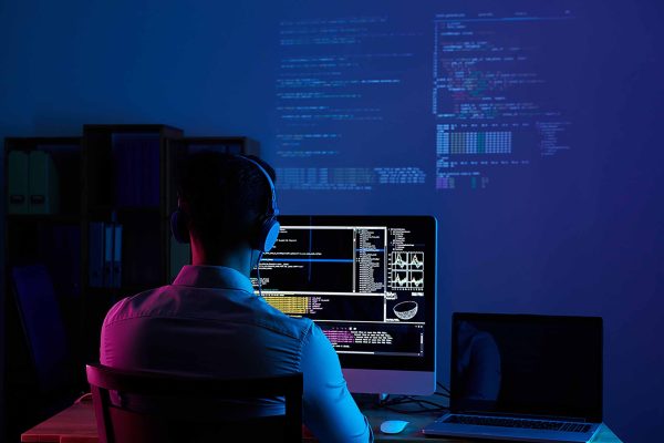 Developer working on code late at night, view from the back